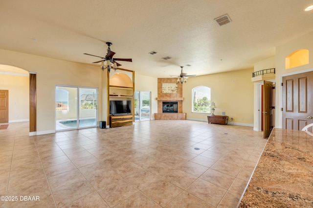 4690 S Atlantic Ave, Ponce Inlet, FL 32127 - unfurnished living room with a ceiling fan, light tile patterned floors, a fireplace, and arched walkways