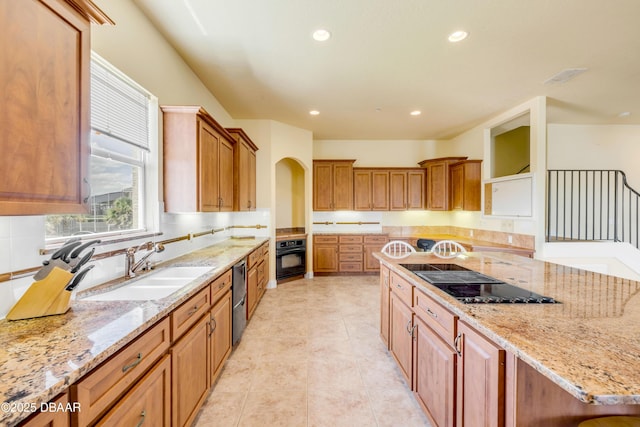 4690 S Atlantic Ave, Ponce Inlet, FL 32127 - kitchen featuring black appliances, light stone countertops, recessed lighting, brown cabinetry, and arched walkways