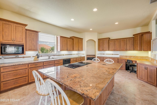 4690 S Atlantic Ave, Ponce Inlet, FL 32127 - kitchen featuring black appliances, a center island, brown cabinets, light stone counters, and recessed lighting