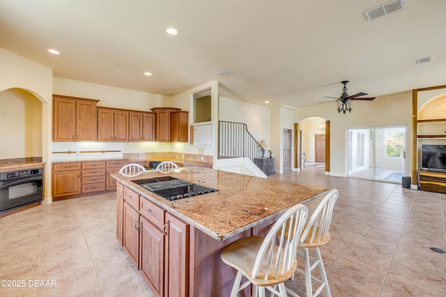 4690 S Atlantic Ave, Ponce Inlet, FL 32127 - kitchen with black appliances, arched walkways, open floor plan, a center island, and light stone counters