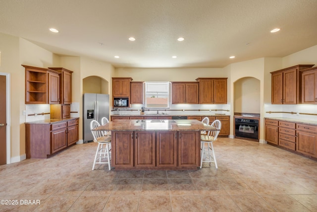 4690 S Atlantic Ave, Ponce Inlet, FL 32127 - kitchen featuring black appliances, a kitchen island, a kitchen bar, brown cabinets, and recessed lighting