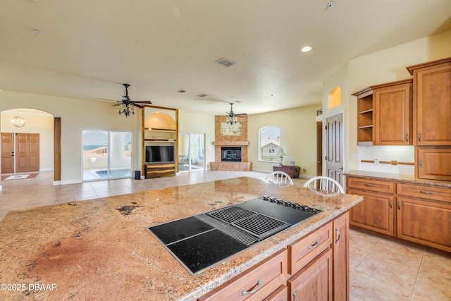 4690 S Atlantic Ave, Ponce Inlet, FL 32127 - kitchen with black electric cooktop, light tile patterned flooring, arched walkways, a large fireplace, and open floor plan
