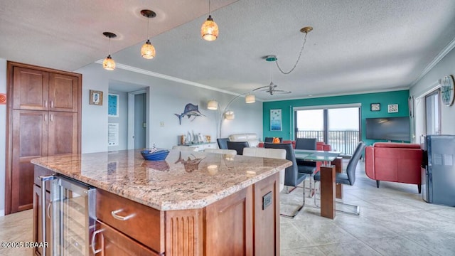 kitchen with light stone counters, a kitchen island, beverage cooler, and hanging light fixtures