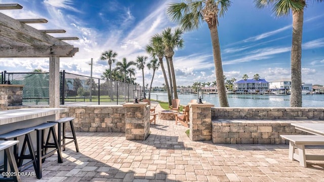 view of patio / terrace featuring a bar, a fire pit, a pergola, and a water view