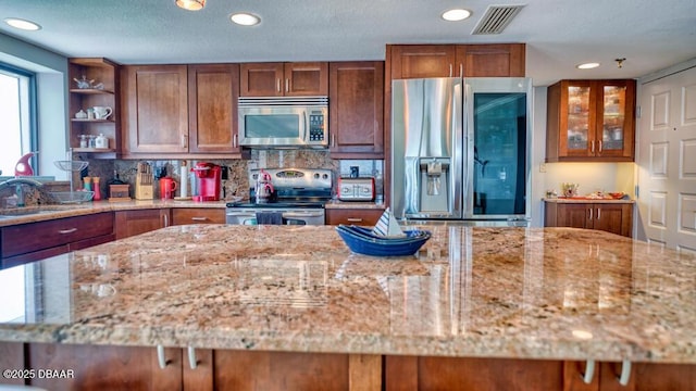 kitchen with stainless steel appliances, tasteful backsplash, sink, and light stone counters