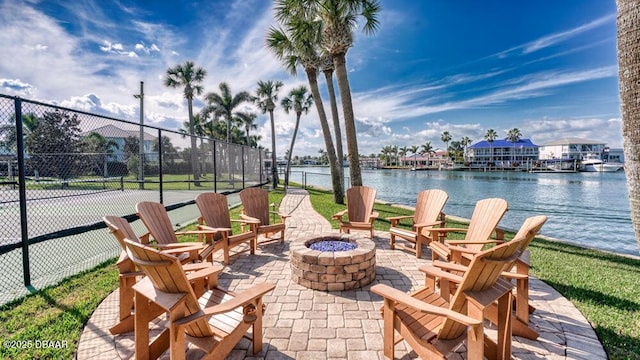 view of patio / terrace featuring a water view, tennis court, and an outdoor fire pit