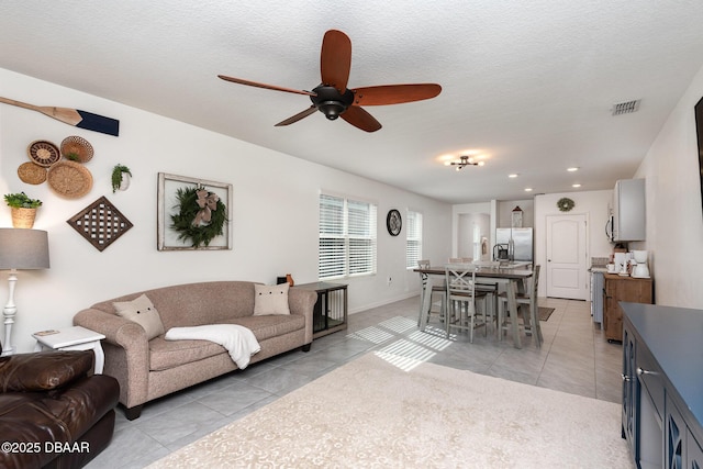 living room featuring ceiling fan, light tile patterned floors, and a textured ceiling