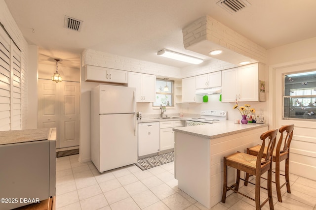 kitchen with visible vents, under cabinet range hood, white appliances, a peninsula, and white cabinets