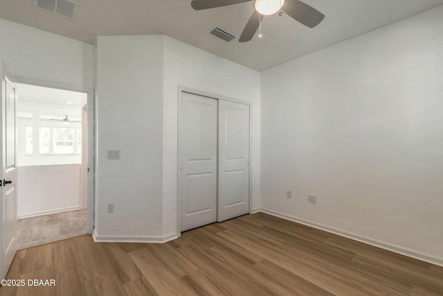 unfurnished bedroom featuring baseboards, wood finished floors, and visible vents
