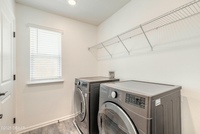 clothes washing area featuring laundry area, baseboards, wood finished floors, and separate washer and dryer