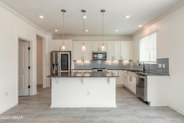 kitchen with crown molding, a kitchen island, white cabinetry, a sink, and stainless steel appliances