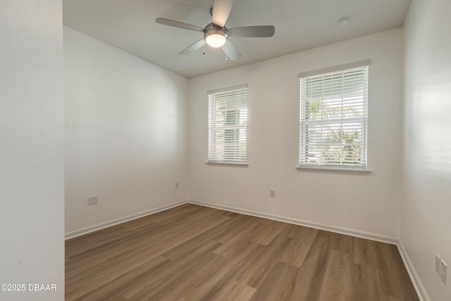 spare room featuring baseboards, wood finished floors, and a healthy amount of sunlight
