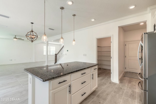 kitchen featuring crown molding, dark stone counters, ceiling fan, and freestanding refrigerator
