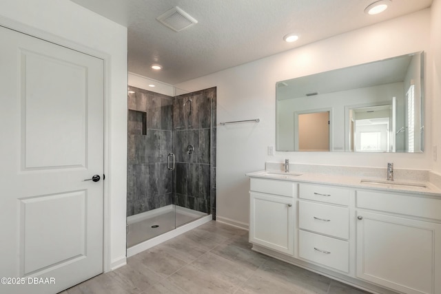 full bathroom with a sink, a stall shower, double vanity, and visible vents