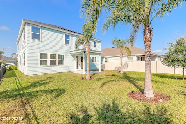 rear view of property with a lawn, fence, and french doors
