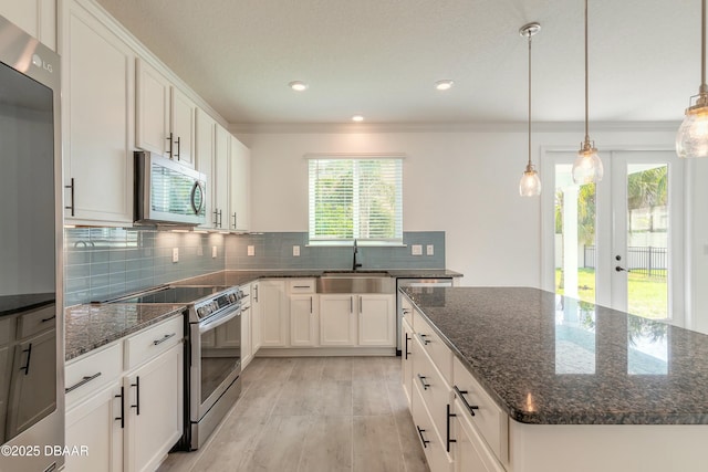 kitchen with decorative backsplash, crown molding, a center island, a sink, and stainless steel appliances