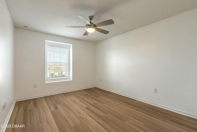 empty room featuring baseboards, a ceiling fan, a textured ceiling, and wood finished floors