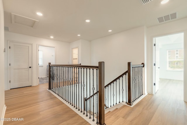 hallway with visible vents, recessed lighting, wood finished floors, and an upstairs landing