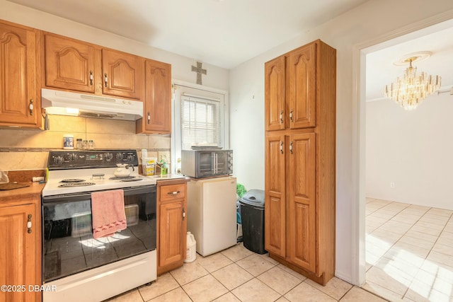 kitchen featuring decorative backsplash, white range with electric stovetop, light tile patterned floors, pendant lighting, and a chandelier