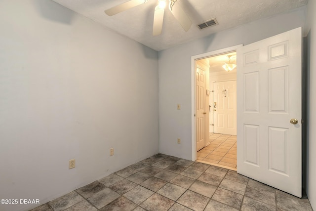 tiled spare room with ceiling fan and a textured ceiling