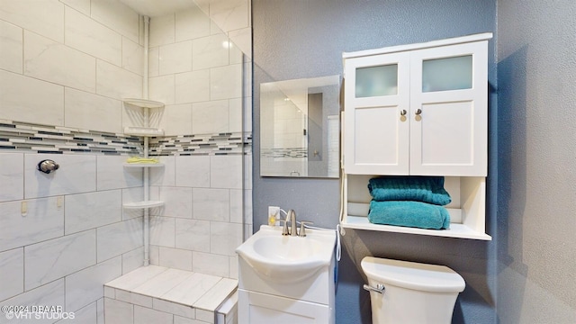 bathroom with tiled shower, vanity, and toilet