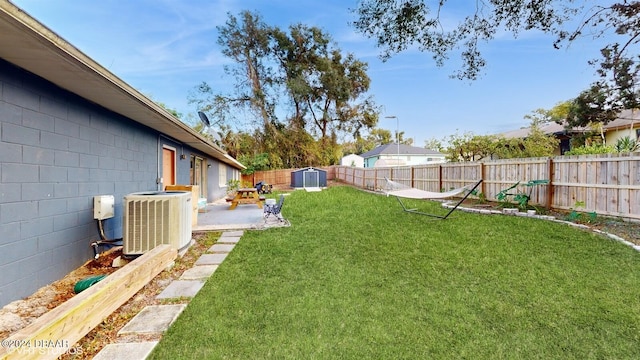 view of yard featuring central AC, a storage unit, and a patio area