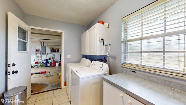 clothes washing area with cabinets, a textured ceiling, a wealth of natural light, and washing machine and clothes dryer