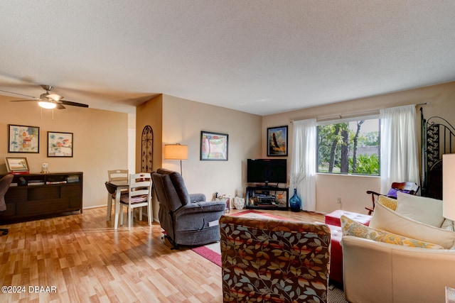 living room featuring ceiling fan, a textured ceiling, and light hardwood / wood-style floors