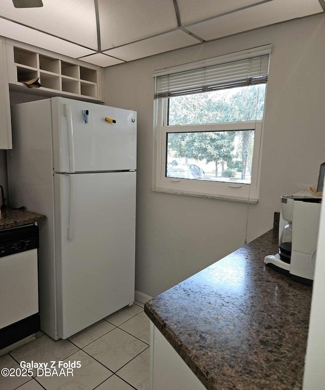 kitchen with a paneled ceiling, white cabinets, white refrigerator, stainless steel dishwasher, and light tile patterned floors