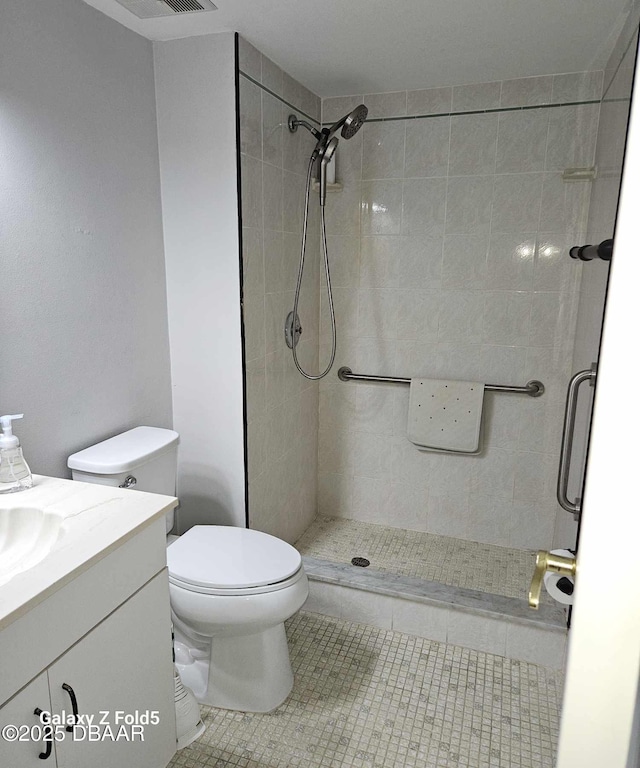 bathroom with vanity, a tile shower, tile patterned floors, and toilet