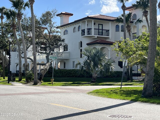 view of front of home with stucco siding, a front lawn, and a tiled roof