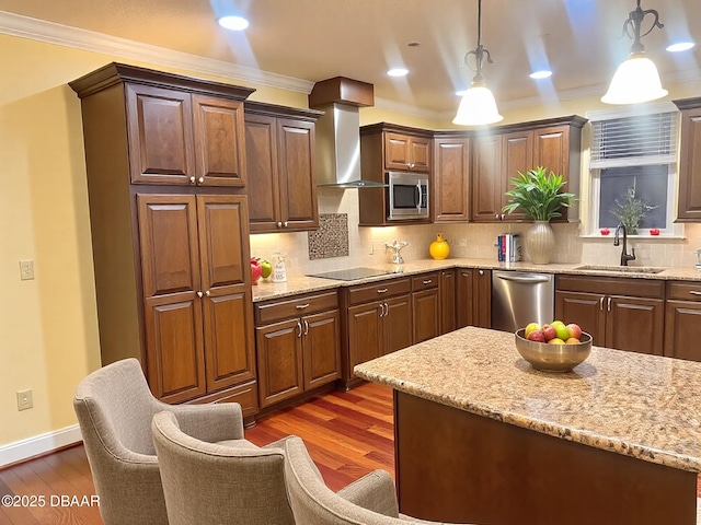 kitchen with appliances with stainless steel finishes, crown molding, a sink, and wall chimney range hood