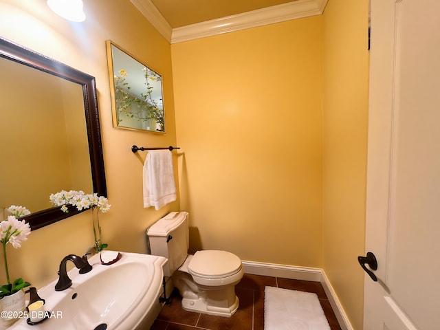 half bathroom featuring ornamental molding, baseboards, toilet, and tile patterned floors