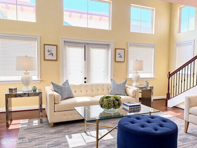 living room featuring stairs, a high ceiling, wood finished floors, and baseboards