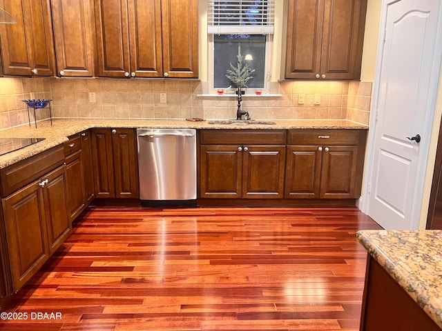 kitchen with a sink, dark wood-style floors, light stone countertops, dishwasher, and tasteful backsplash