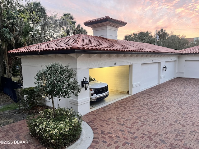 view of side of home featuring a tiled roof, decorative driveway, and stucco siding