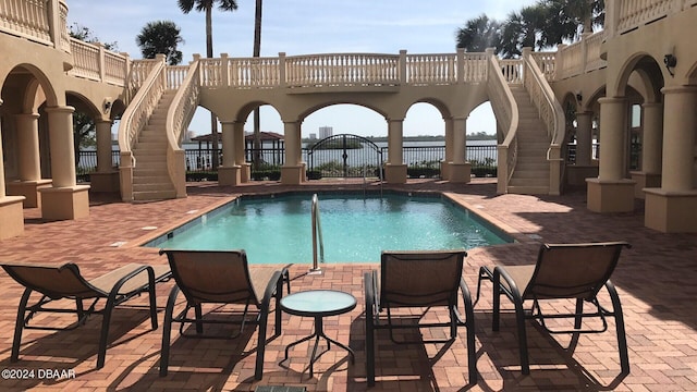 community pool featuring a patio area, fence, and stairway