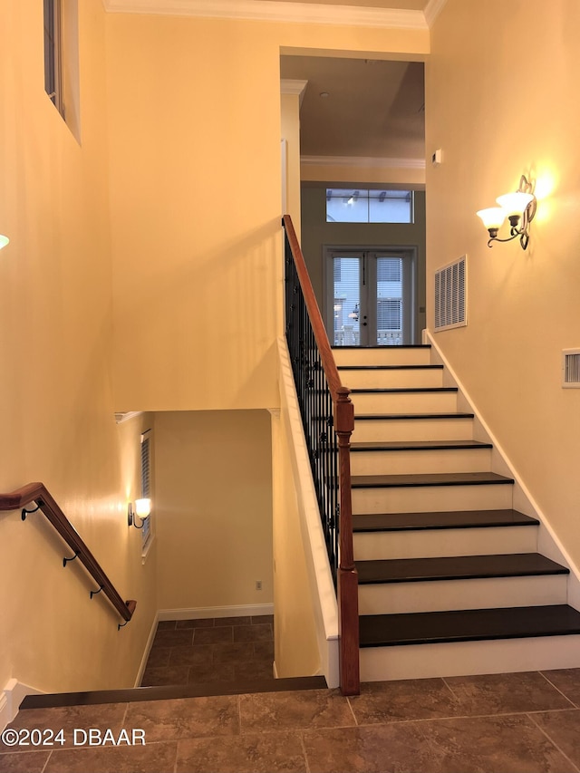 staircase with baseboards, visible vents, and ornamental molding