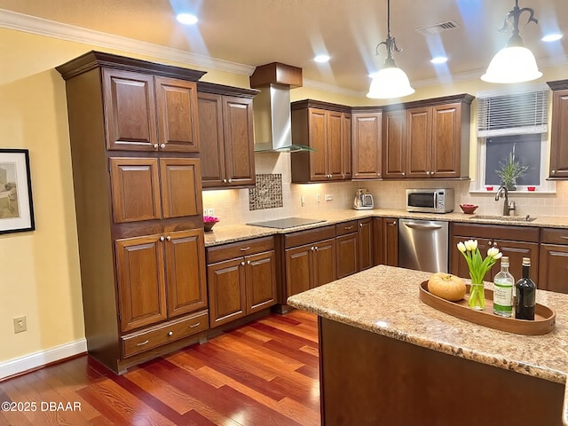 kitchen with a sink, visible vents, ornamental molding, appliances with stainless steel finishes, and wall chimney range hood