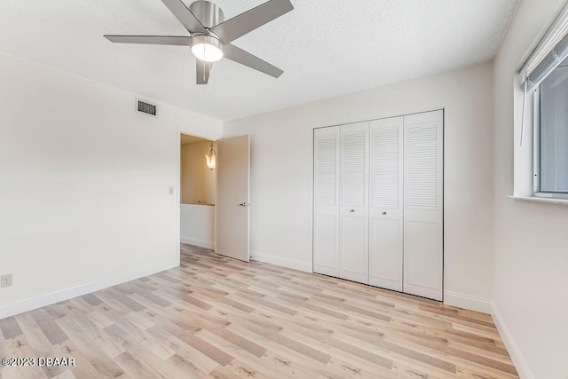 unfurnished bedroom with light hardwood / wood-style floors, ceiling fan, a textured ceiling, and a closet