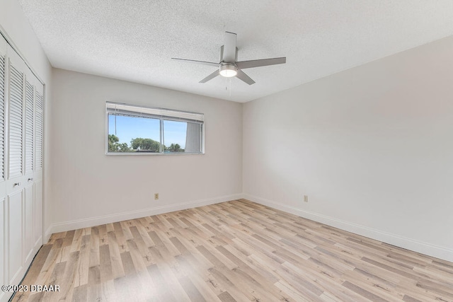 unfurnished bedroom with a closet, light wood-type flooring, a textured ceiling, and ceiling fan