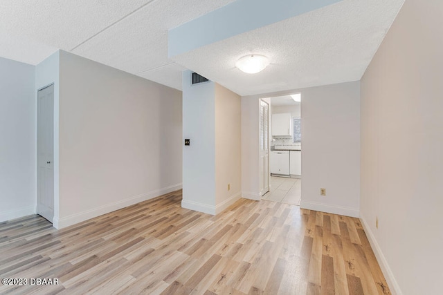 empty room with a textured ceiling and light hardwood / wood-style floors