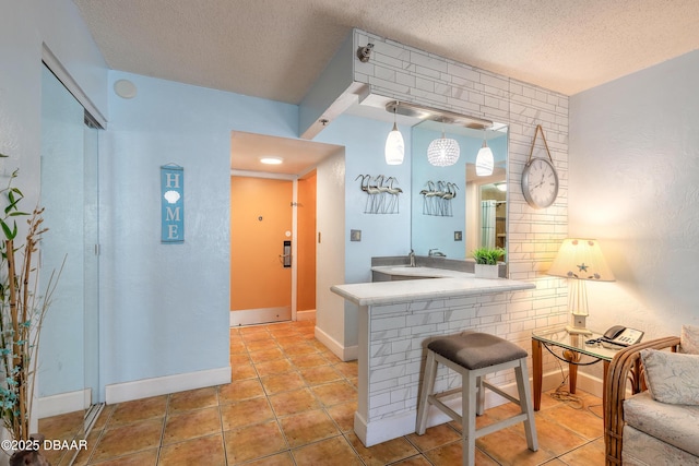 313 S Atlantic Avenue 302 & 304, Daytona Beach, FL 32118 - kitchen with a textured ceiling, light tile patterned flooring, a breakfast bar, a peninsula, and light countertops