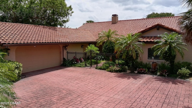 6 Rosalyn Lndg, Daytona Beach, FL 32118 - mediterranean / spanish-style home featuring a garage, stucco siding, a chimney, a tile roof, and decorative driveway