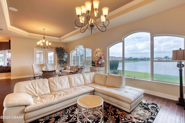 living room featuring dark hardwood / wood-style flooring, a water view, a chandelier, and a raised ceiling