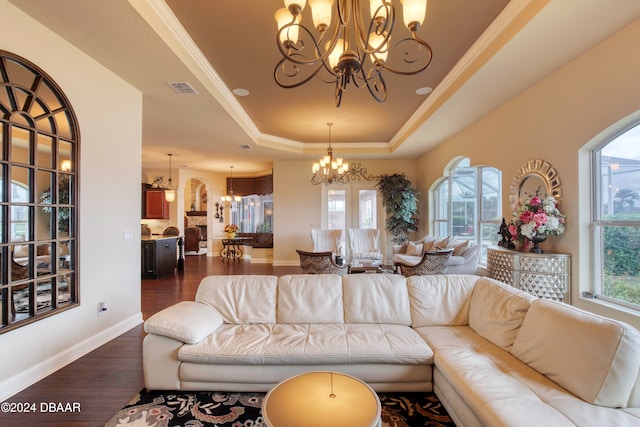 living room featuring a chandelier, a raised ceiling, a healthy amount of sunlight, and dark hardwood / wood-style floors