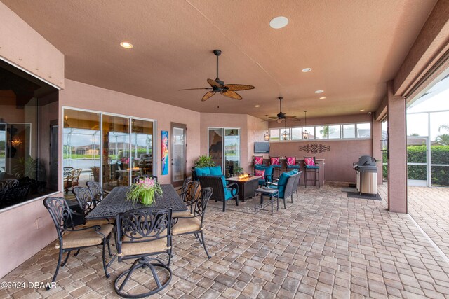 view of patio with ceiling fan, area for grilling, and an outdoor living space with a fire pit