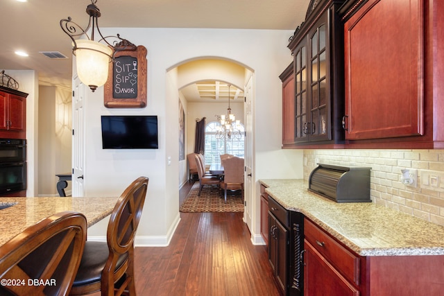 kitchen featuring dark wood-type flooring, light stone countertops, and backsplash