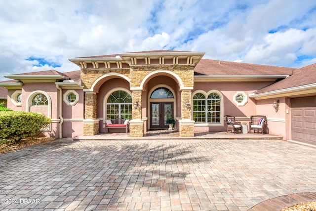 property entrance featuring a patio area, french doors, and a garage