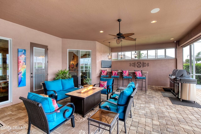 view of patio / terrace with an outdoor living space with a fire pit, a bar, area for grilling, and ceiling fan